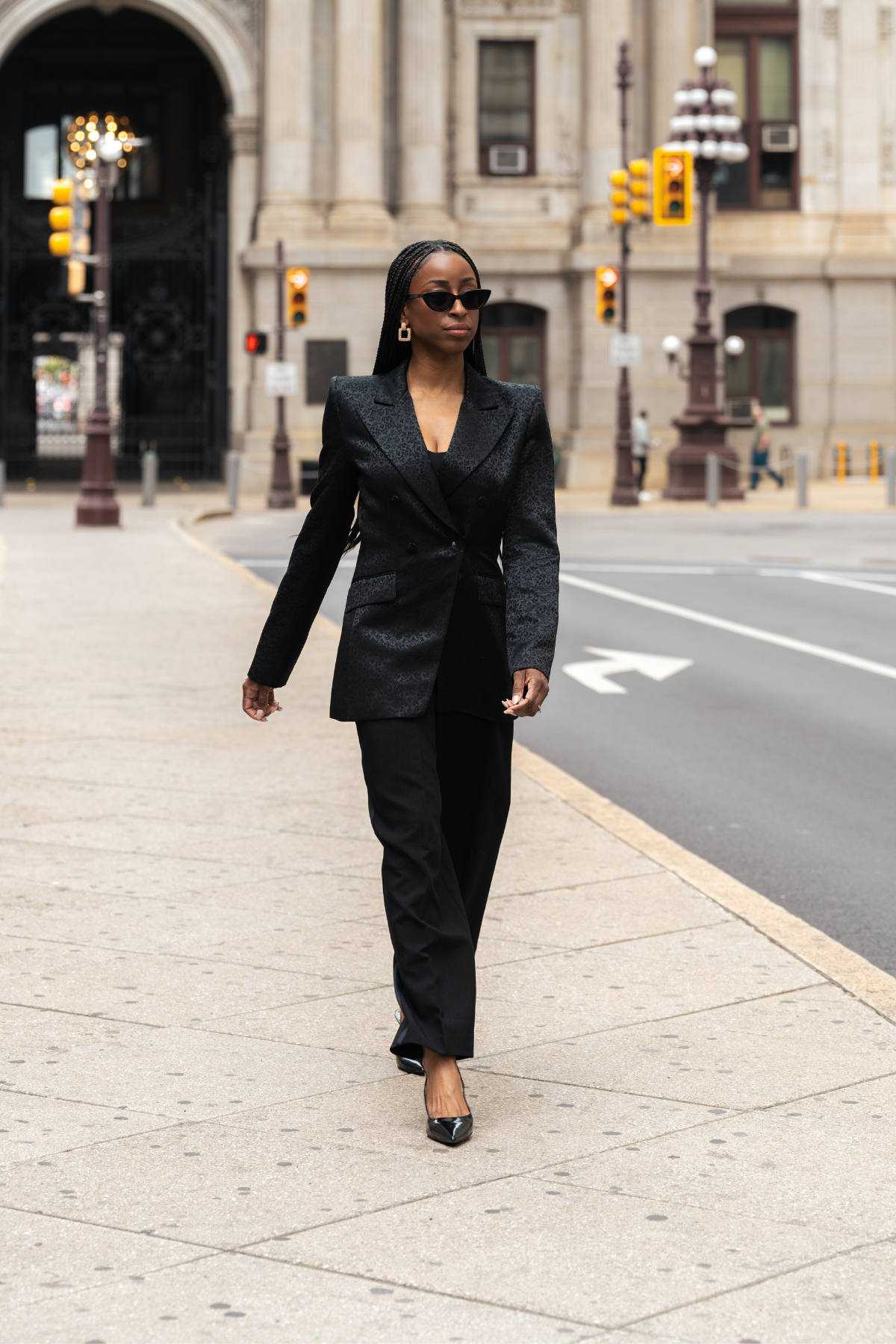 Woman in a black suit walking on a city street.