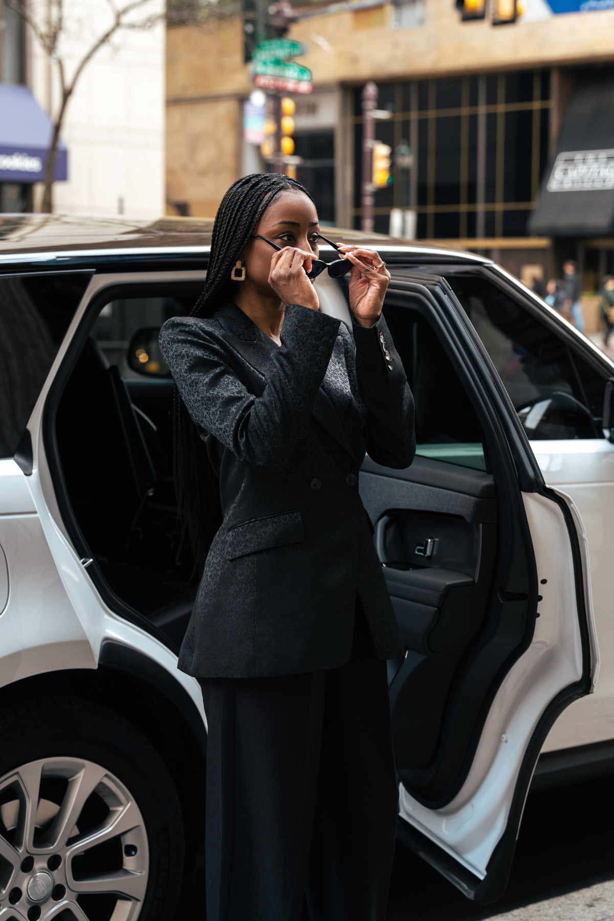 Woman getting out of a white car on a city street wearing a Black Blazer