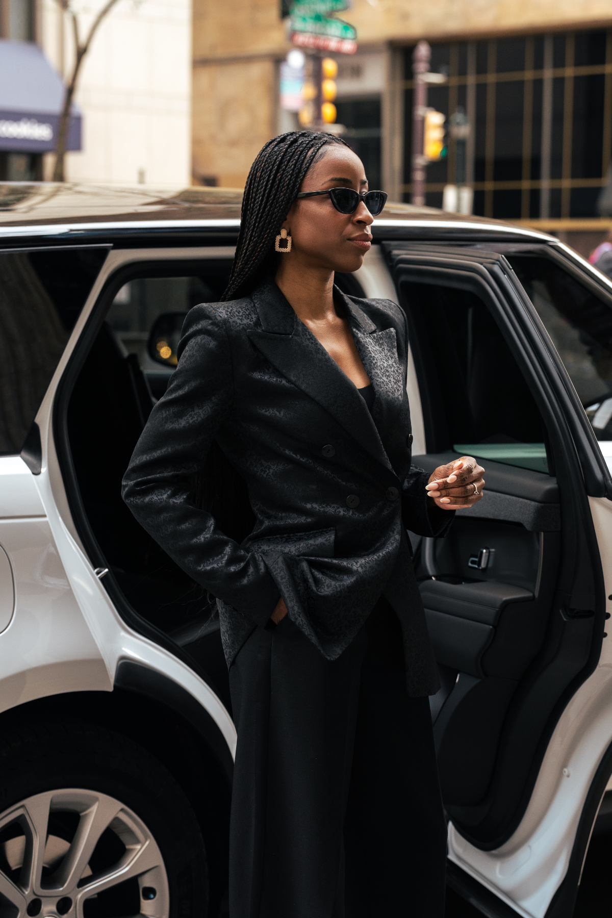 Woman in a black coat stepping out of a white car in an urban setting