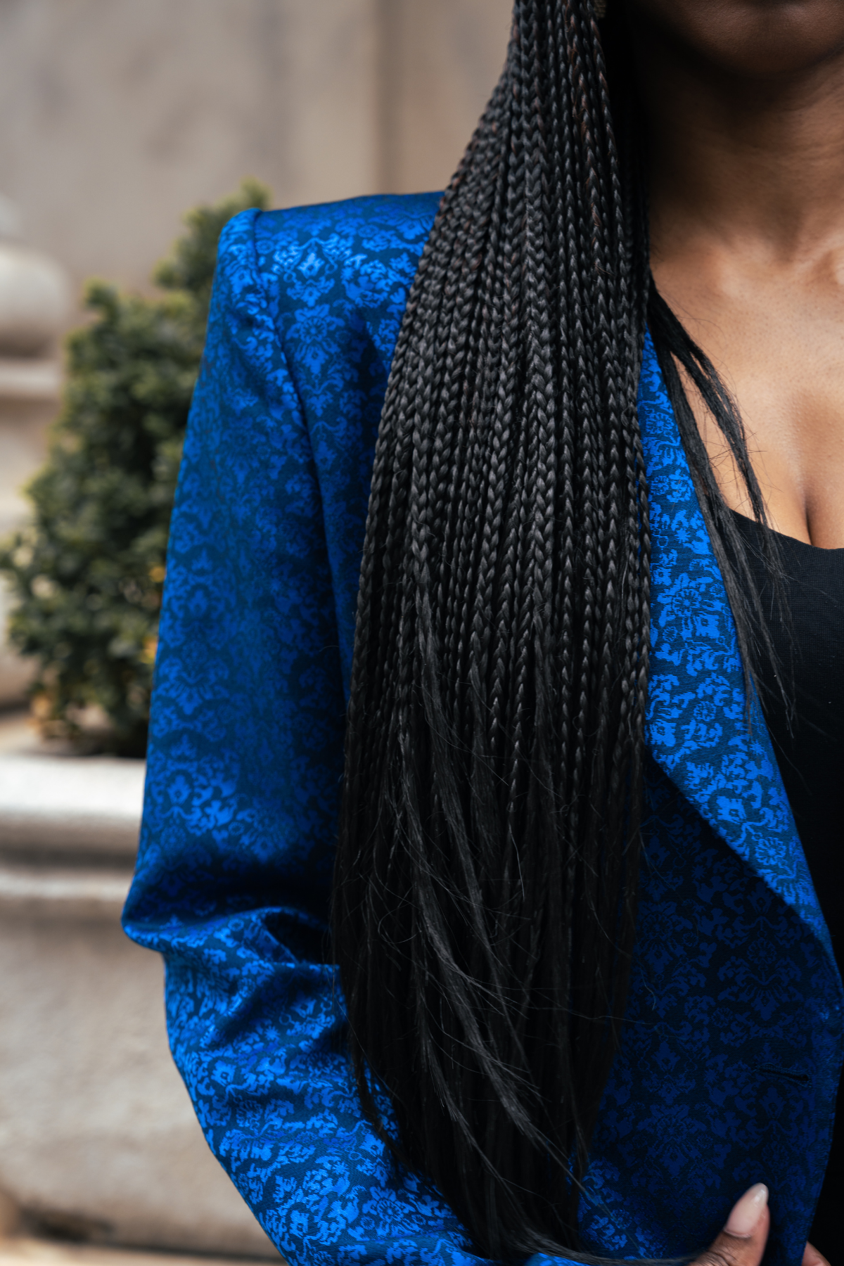 Person wearing a blue jacket with braided hair, blurred background
