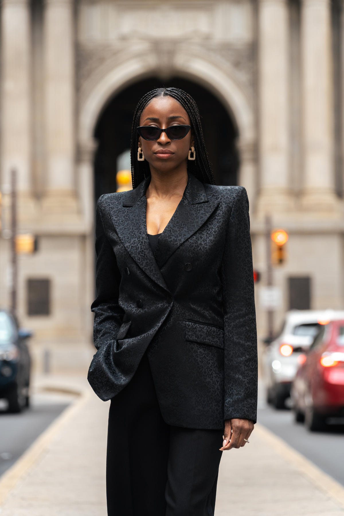 Woman in a black suit standing on a city street with a blurred background