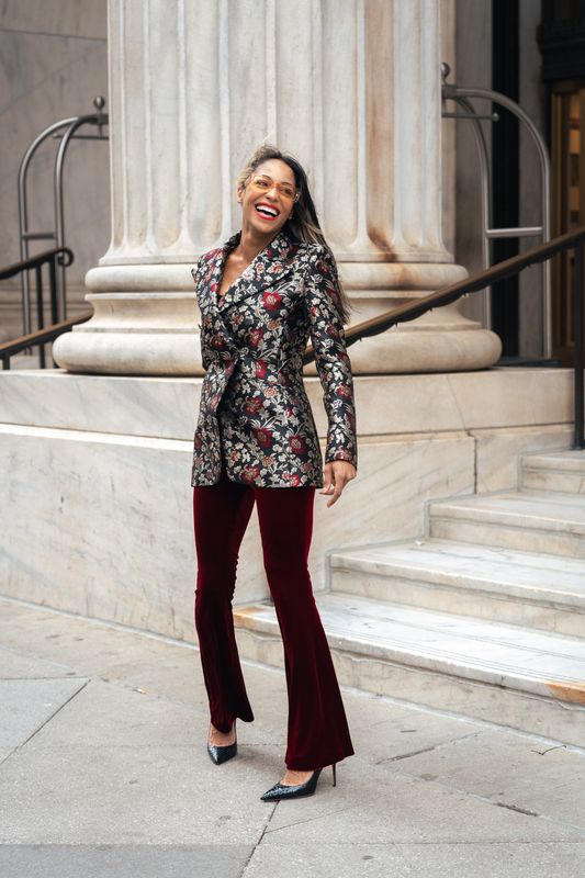 Woman in a floral blazer and red pants standing on steps in an urban setting