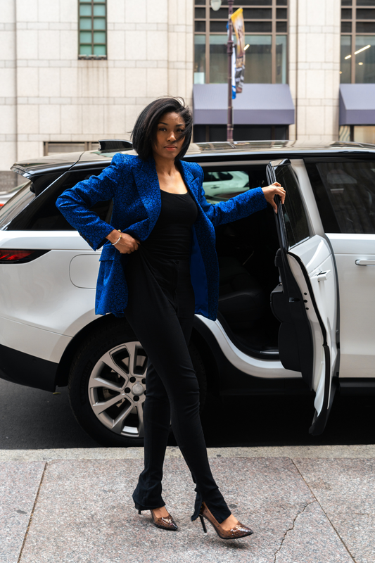 Woman in a blue coat stepping out of a white car on a city street.