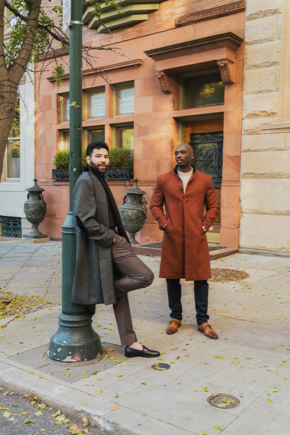 Two men standing on a sidewalk in front of a building with decorative elements.