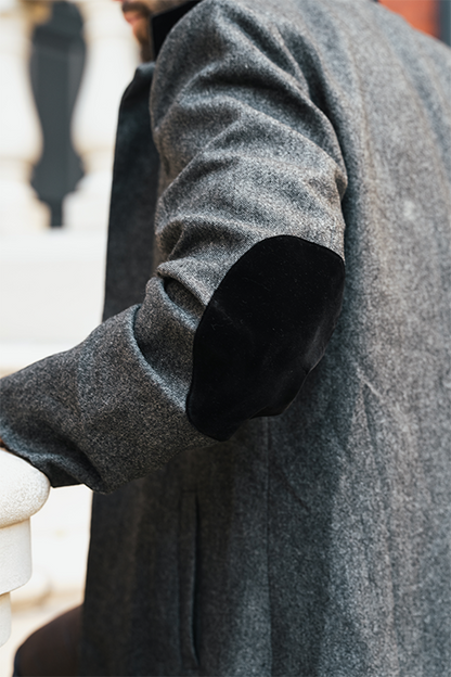 Close-up of a person wearing a gray coat with a blurred background