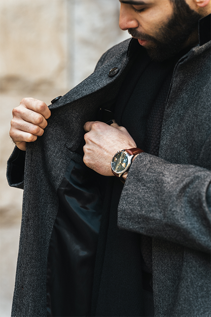 Man adjusting his gray coat with a blurred background