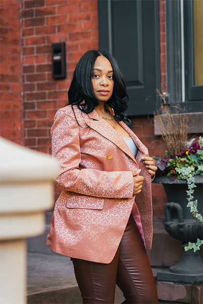Woman in a pink coat standing in front of a brick building