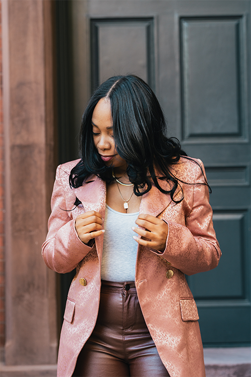 Woman wearing a pink coat standing in front of a door.