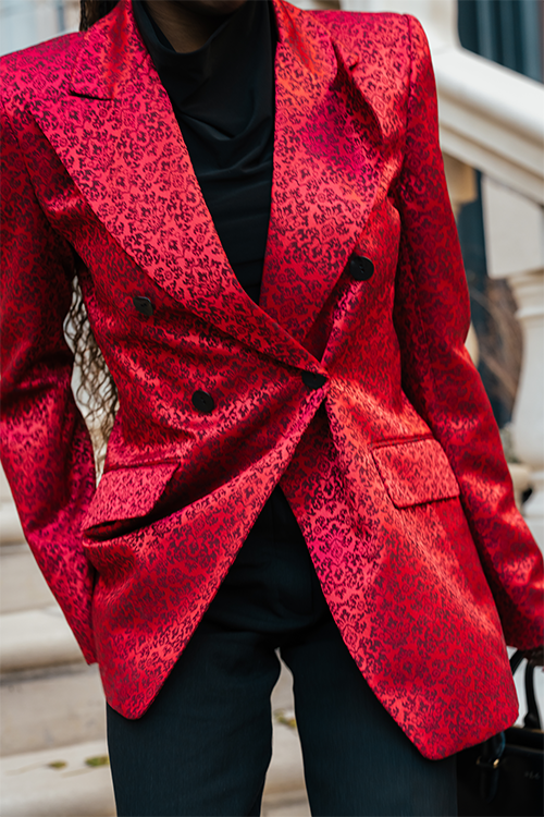 Red patterned blazer worn by a person, with a blurred background